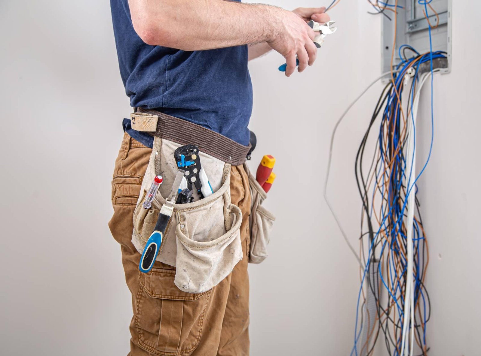 electrician builder work examines cable connection electrical line fuselage industrial switchboard professional overalls with electrician s tool.jpg