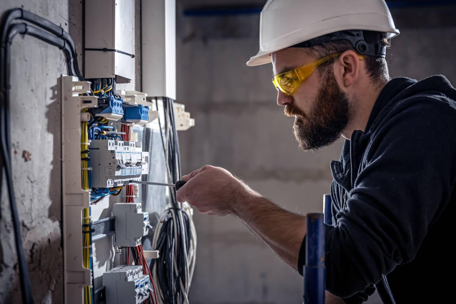male electrician works switchboard with electrical connecting cable.jpg